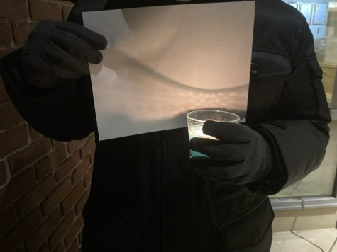 A participant at the vigil holds up a candle and a sheet of blank paper. (Grady Short/The Williams Record)
